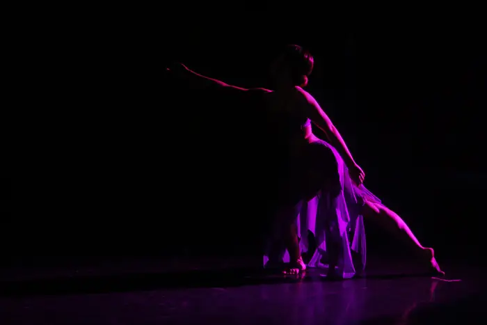 Silhueta de bailarina em movimento, sob luz violeta