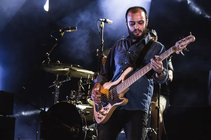Baixista em palco, com bateria ao fundo