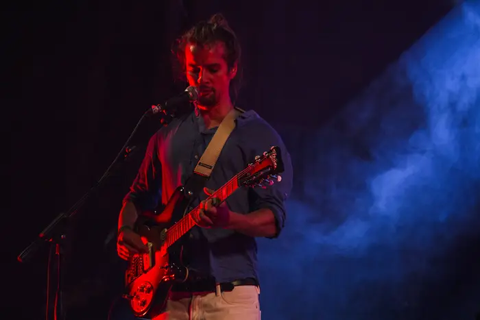 Guitarrista a cantar, sob luz vermelha e azul
