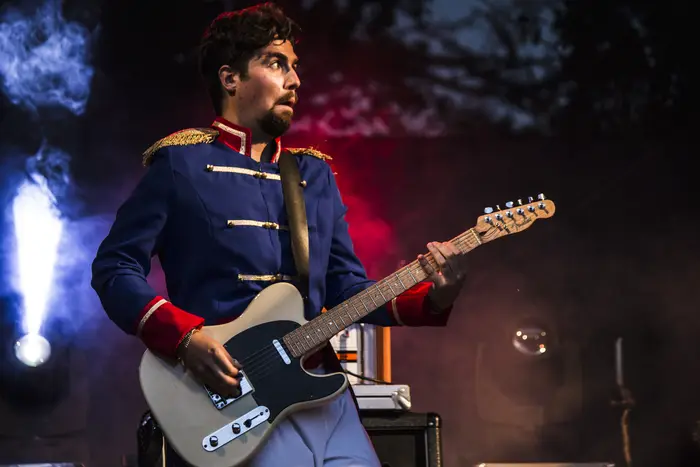 Guitarrista com casaco de estilo militar em palco