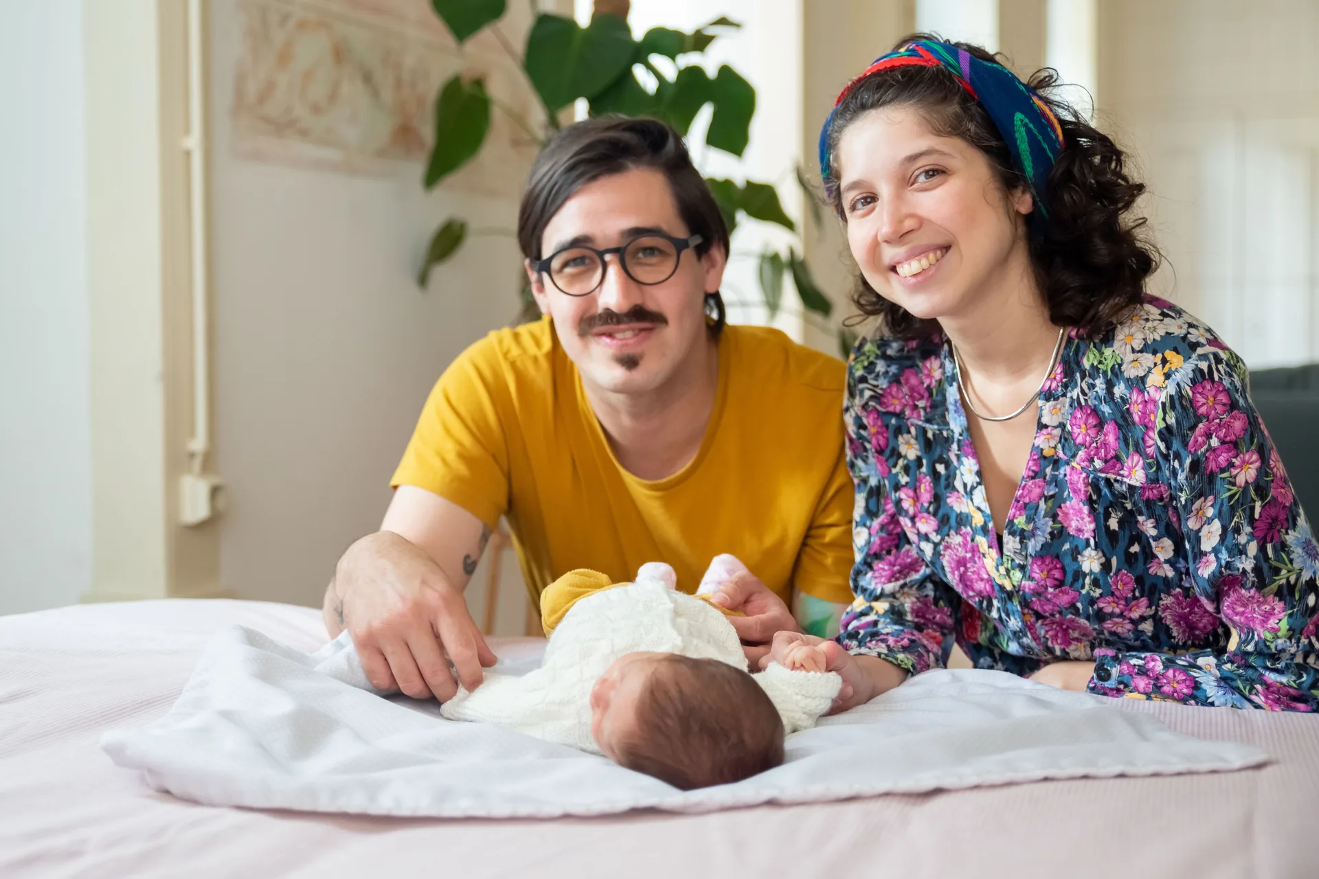Pais sorridentes junto ao seu bebé recém-nascido
