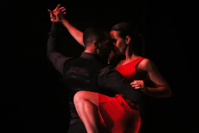 Par de dança abraçado em palco, sob luz vermelha