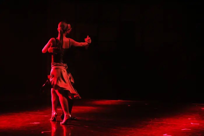 Bailarina sozinha em palco, sob luz vermelha
