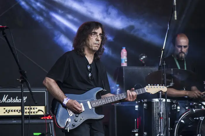 Guitarrista de cabelo comprido em palco, com baterista atrás