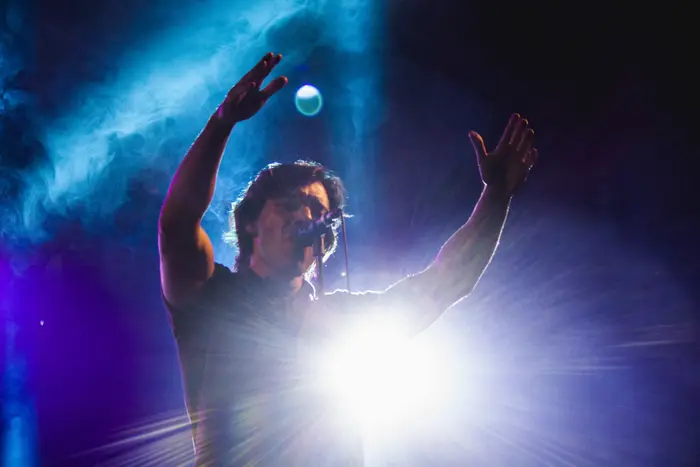 Vocalista em contraluz, com um foco de luz forte atrás