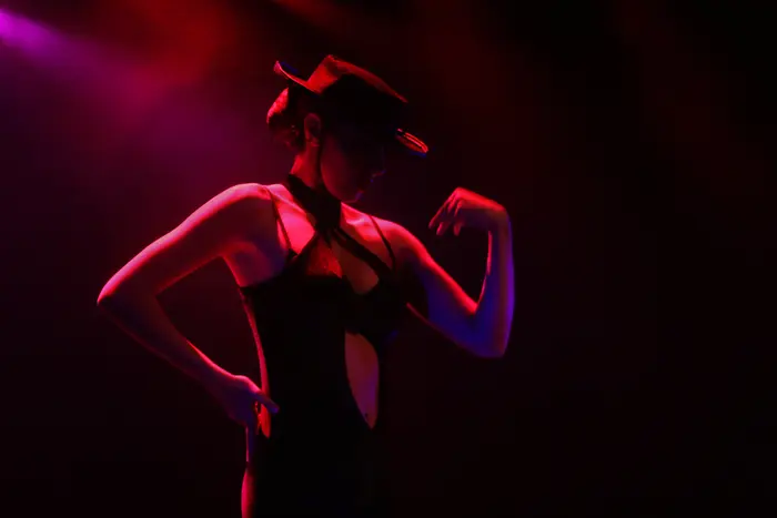Bailarina de chapéu em palco, iluminada por luz vermelha