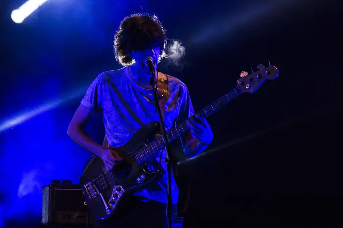 Baixista em palco, iluminado por luz azul intensa