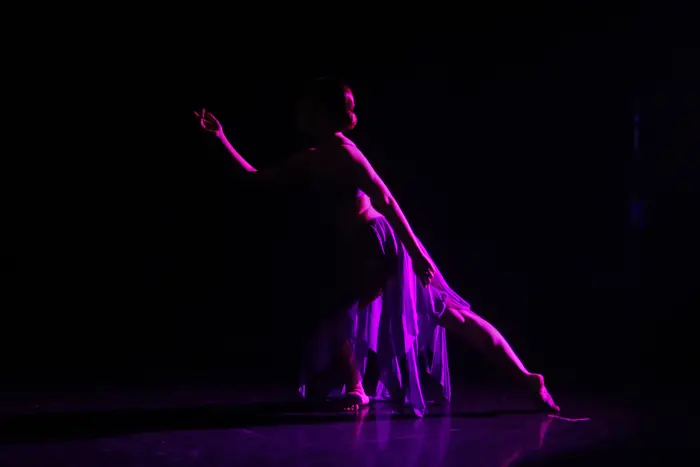 Bailarina com saia longa em movimento, sob luz violeta