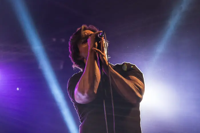 Vocalista a cantar de olhos fechados, segurando o microfone